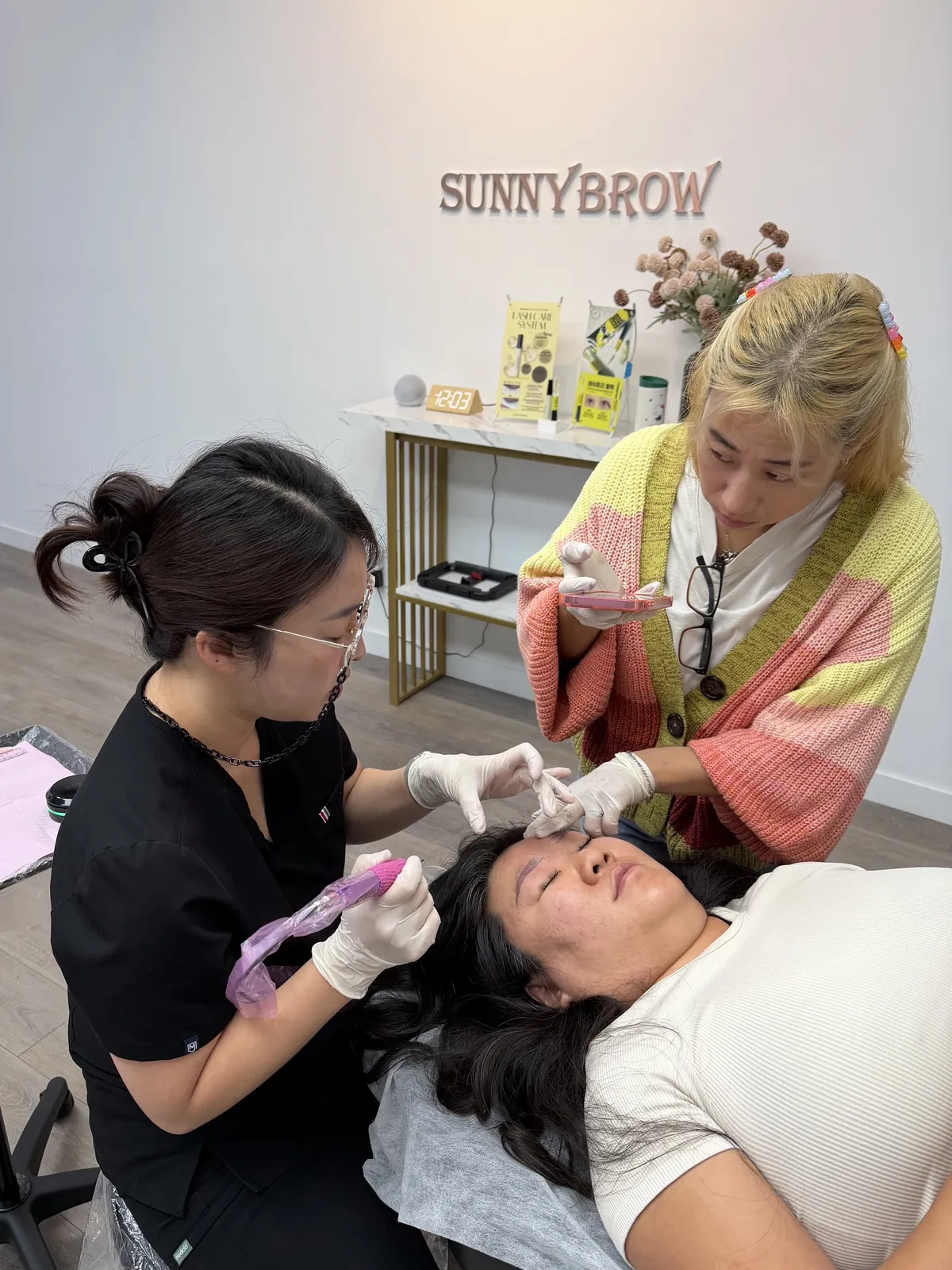 PMU instructor guiding a student's technique during live model eyebrow training at SUNNYBROW Academy, Los Angeles