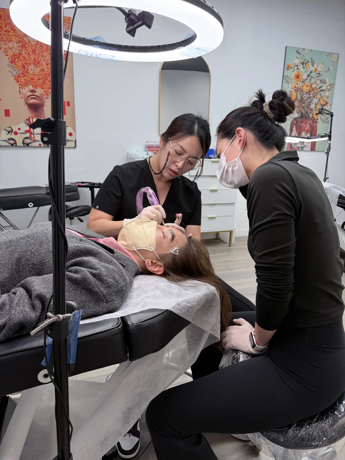 Permanent makeup student working on a live model as the instructor checks her work at a Los Angeles PMU academy