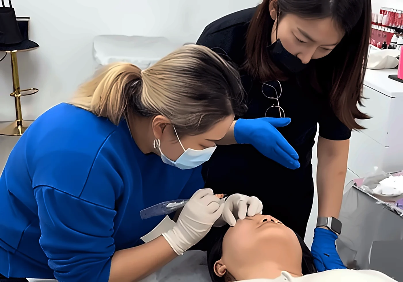 Student performing an eyebrow permanent makeup procedure on a live model with close guidance from Sunny at SUNNYBROW Academy, Los Angeles